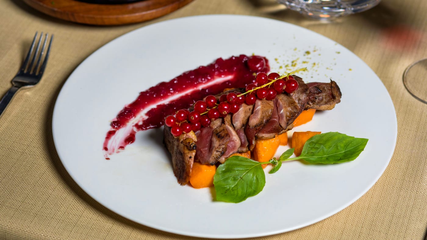 Beef tenderloin served with a red wine sauce and roasted root vegetables, creating a refined and flavorful main course.