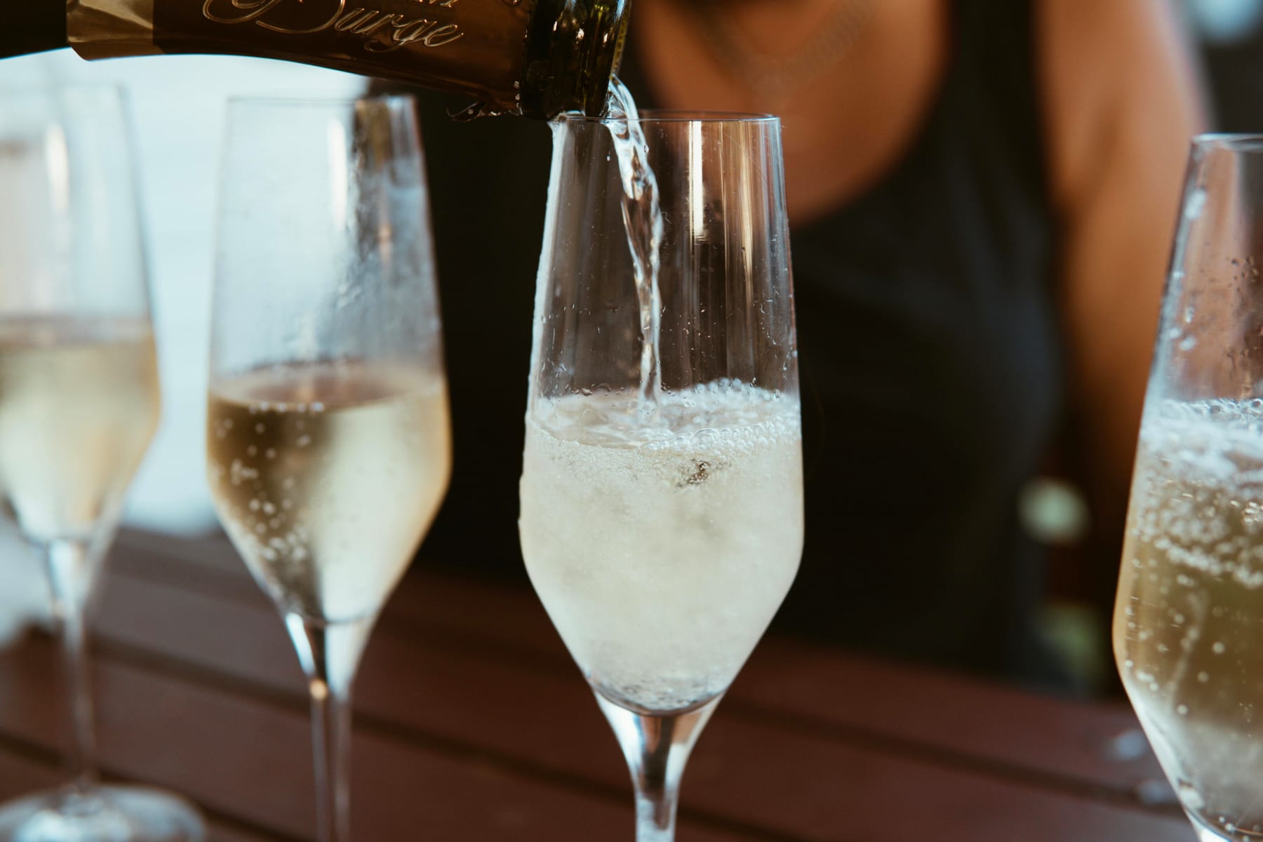 Champagne is poured into tall glasses, ready for New Year's Eve with elegant cocktails.