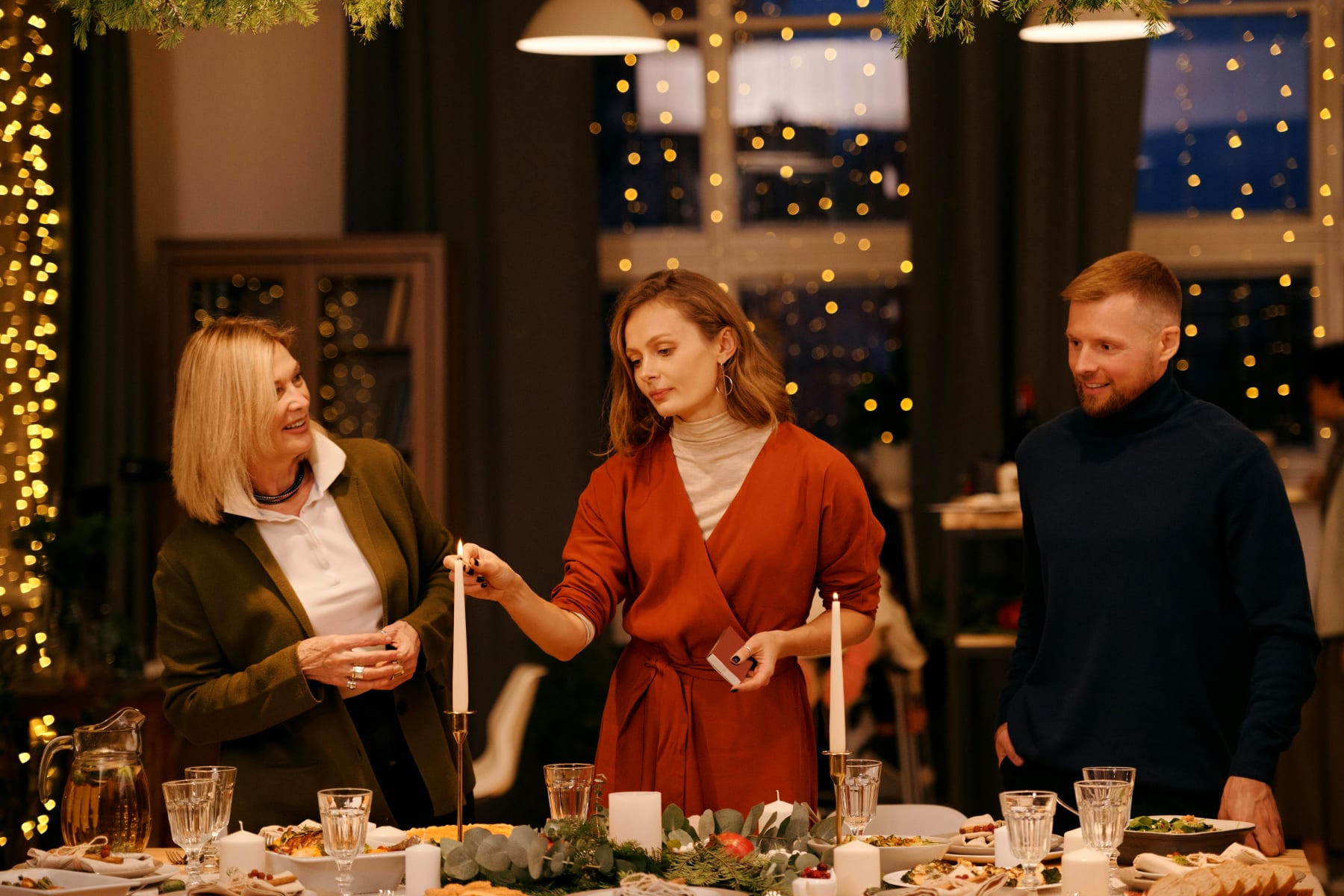 Festive table setting with people enjoying the Christmas lunch in a cozy atmosphere with candles and decorations.