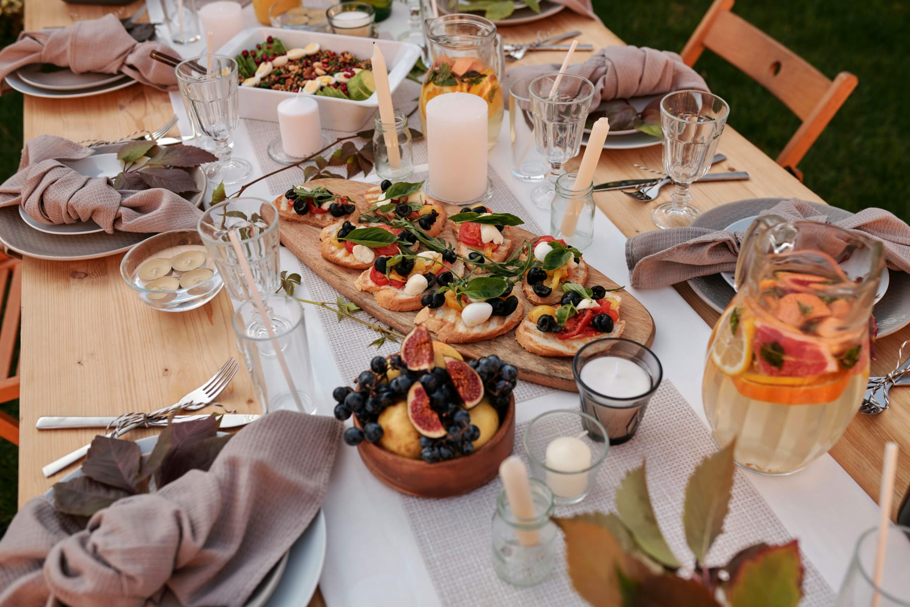 Beautifully set table with delicious food, perfect for a summer company party, including appetizers and refreshing drinks.