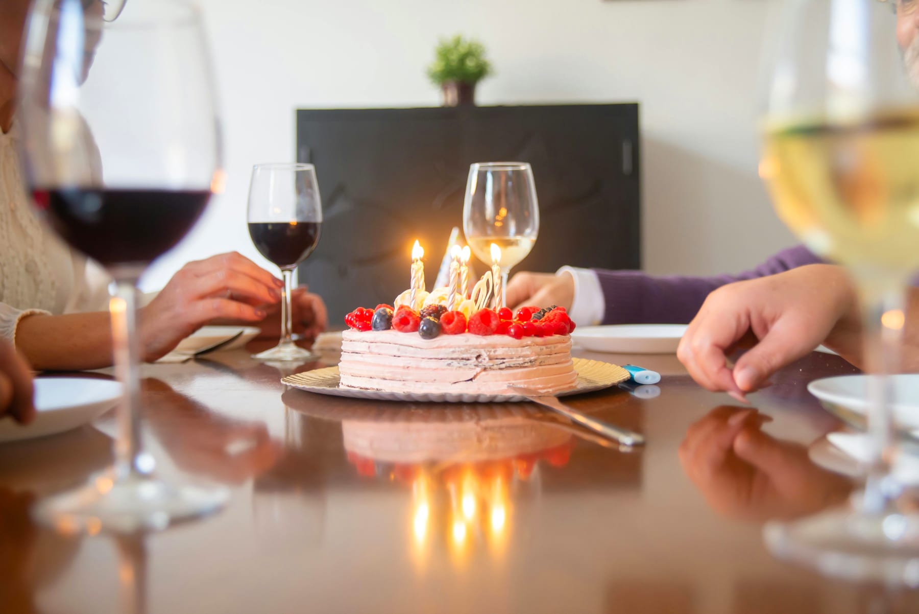 Birthday cake with live candles on a festive table with guests gathered for a 60-year birthday, highlighting the elegant celebration with a private chef.