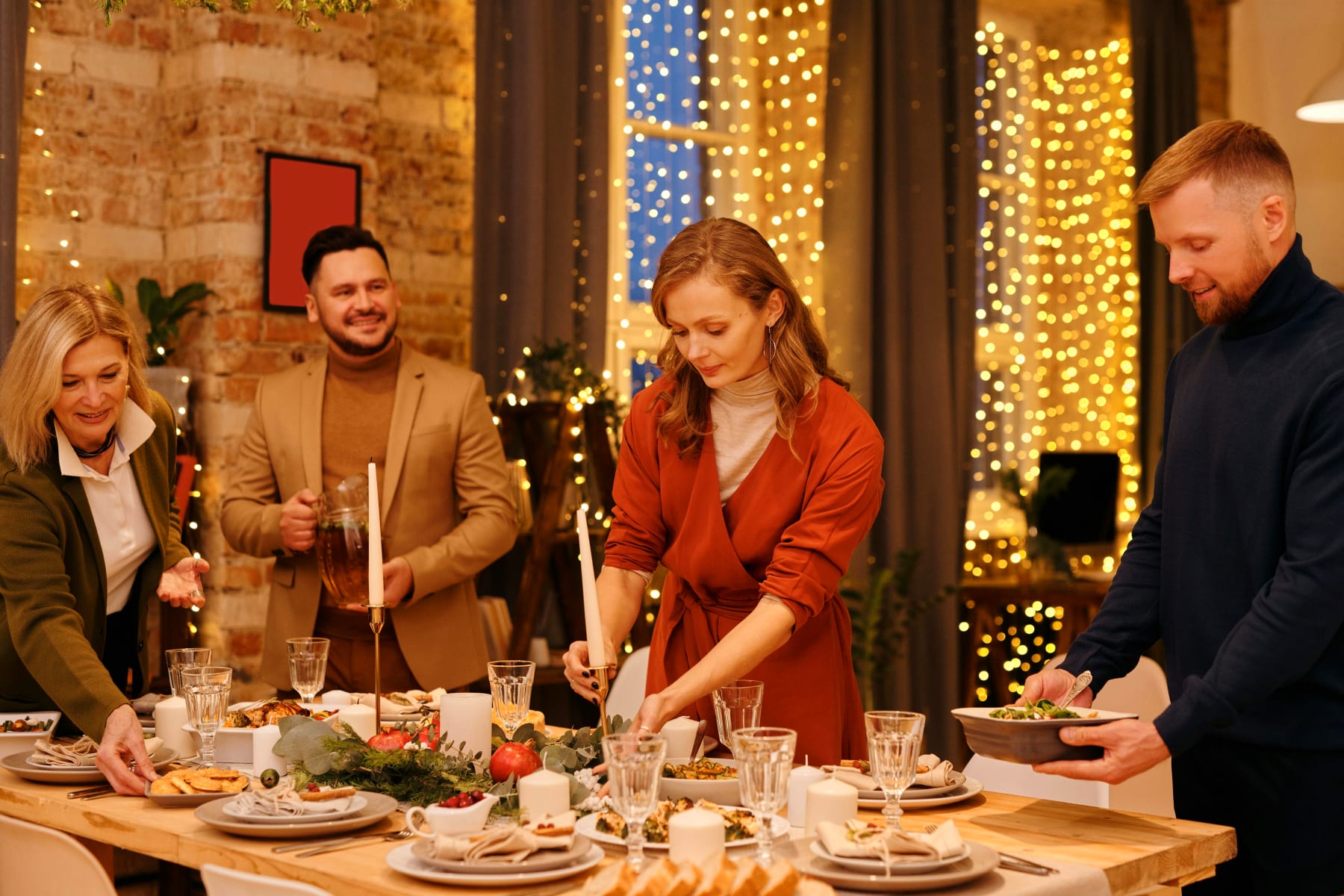 Friends gather around a festively set table with candles and decorative elements, ready to enjoy a gourmet dinner at home.
