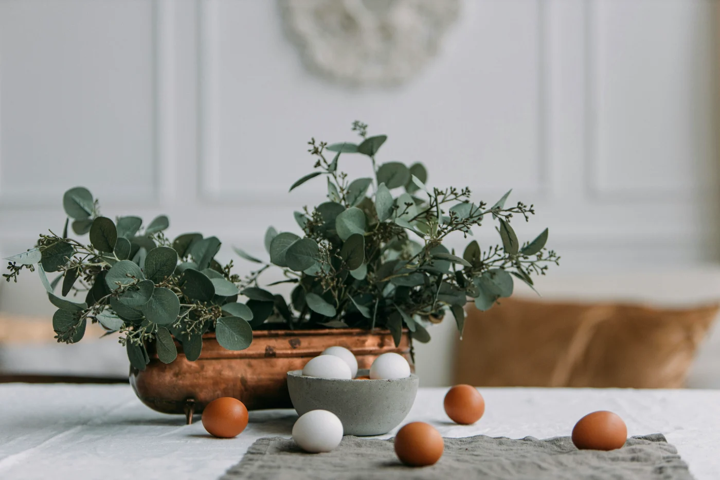 Påskefrokostbord med dekorerede æg og grønne planter, der skaber en forårsinspireret atmosfære til fejring af påsken.