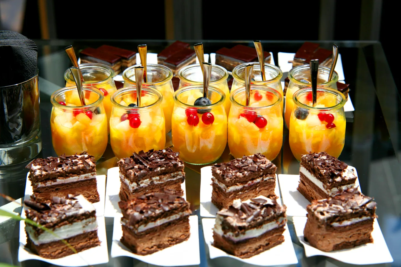 Elegant dessertbord med chokolade- og frugtdesserter, dekorativt serveret i glas og små portioner, ideelt til en festlig afslutning på et måltid.