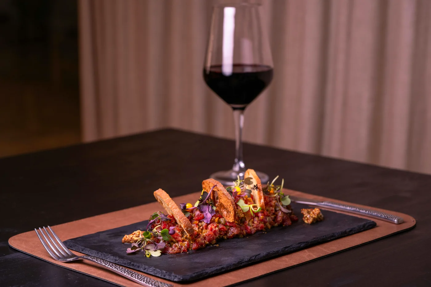 Elegant servering af tatar med et glas rødvin, perfekt til vin parring med nytårsmenuen.