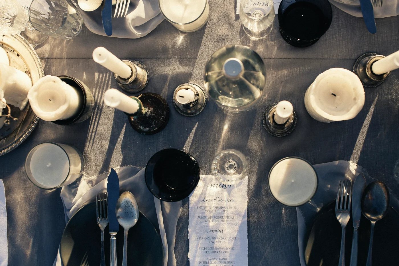 Elegant nytårsbord med stearinlys og stilfuld borddækning, der skaber en intim og festlig atmosfære til aftenen.