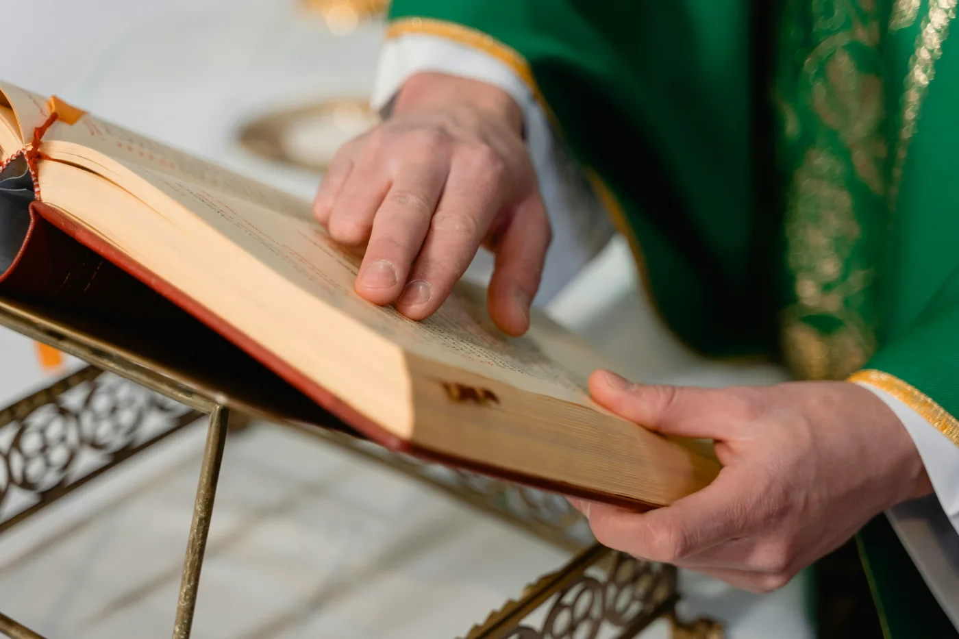 Præst forbereder ceremoni i kirken ved at læse i en åben bibel som del af barnedåbsplanlægning.