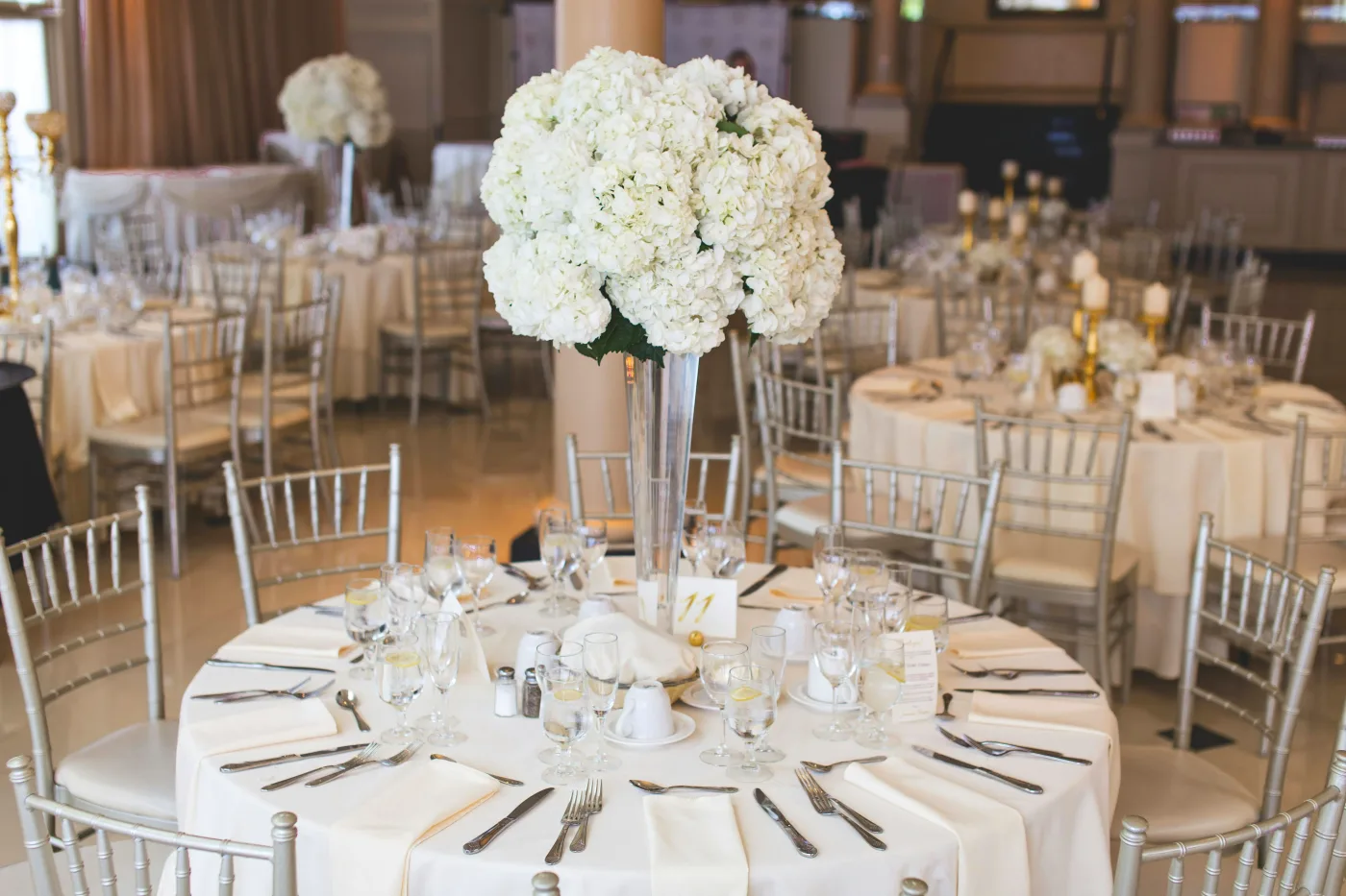 Elegant borddækning med blomsterdekoration ved festlokation, ideel til barnedåb med fokus på dekoration og atmosfære.