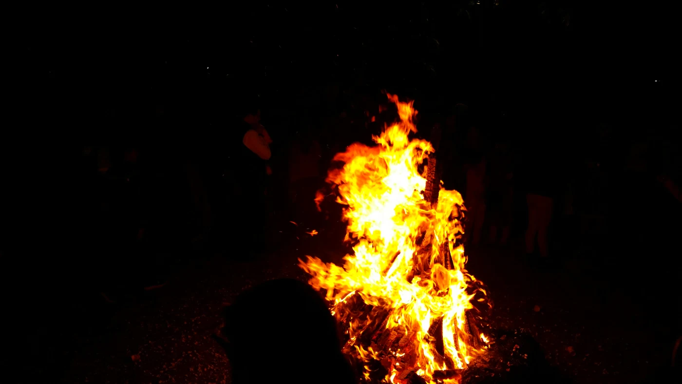 Traditionelt Sankt Hans bål med flammer, der symboliserer fællesskab og fejring af midsommeren i Danmark, hvor folk samles for at synge og nyde natten.