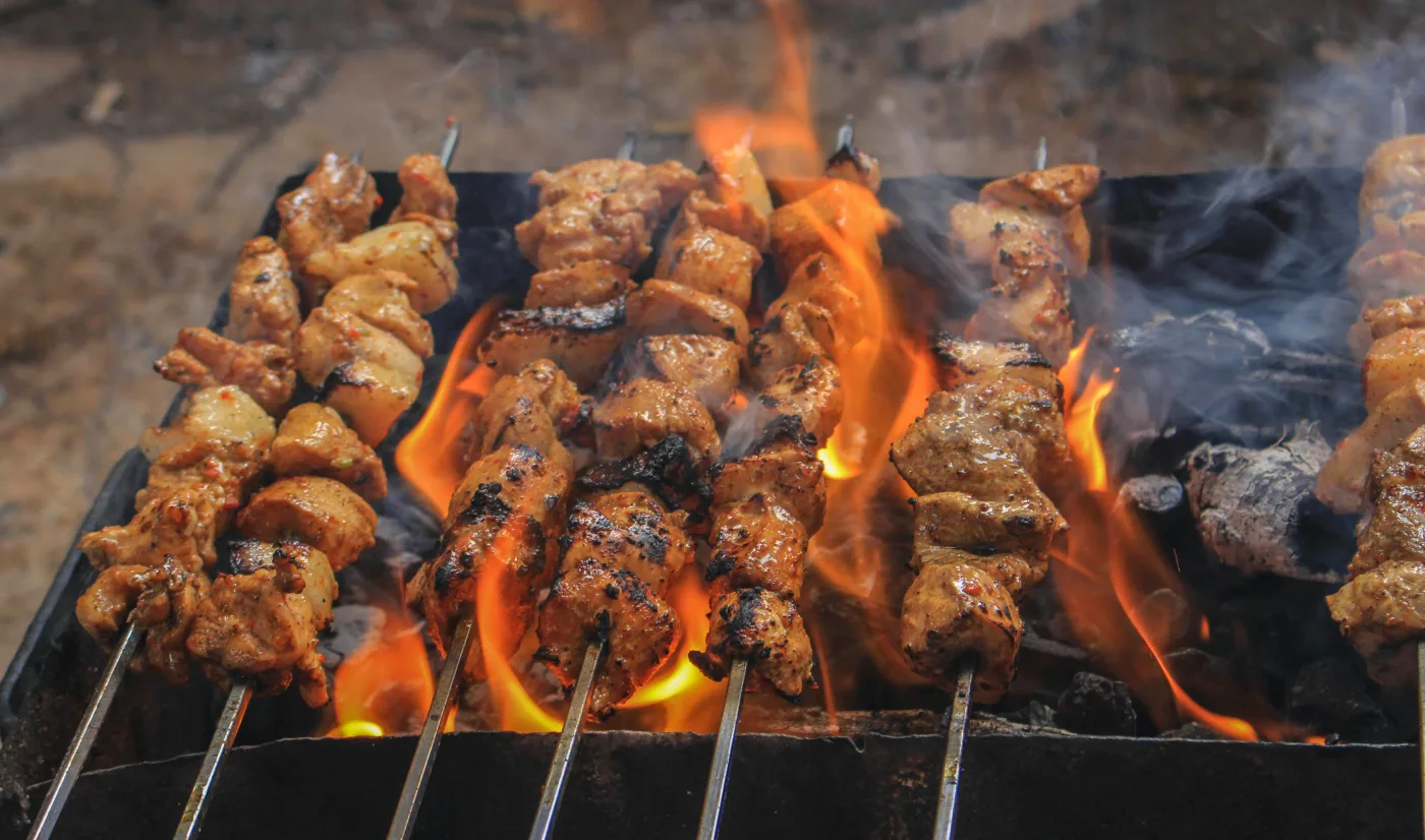 Saftige kødspyd i flammer på grillen, perfekt til Sankt Hans aften og fællesskab.