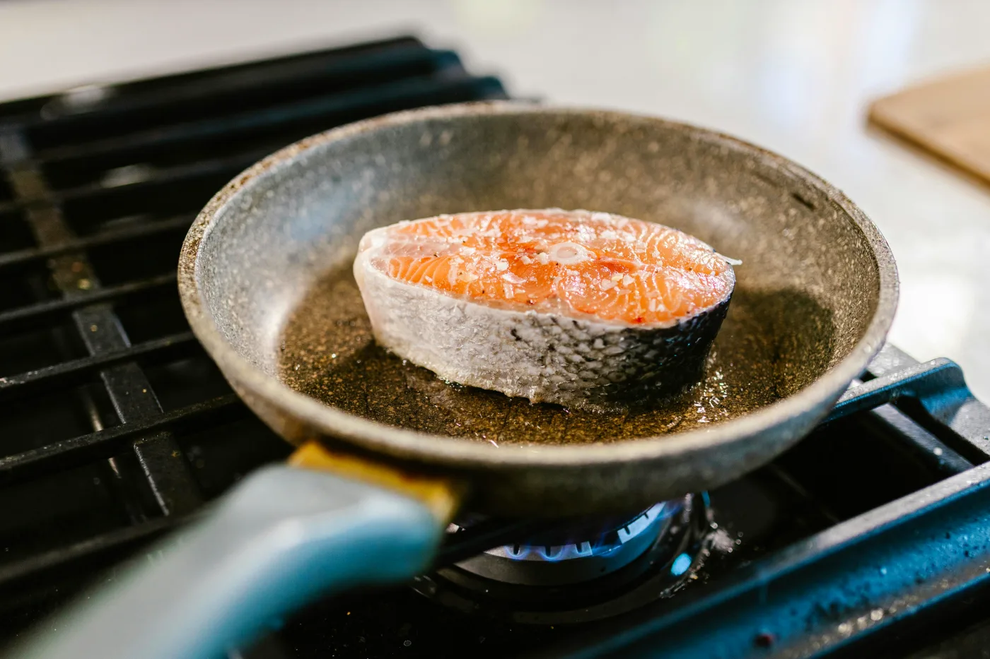 Salmon steak being pan-fried, emphasizes fish preparation techniques and flavor development.