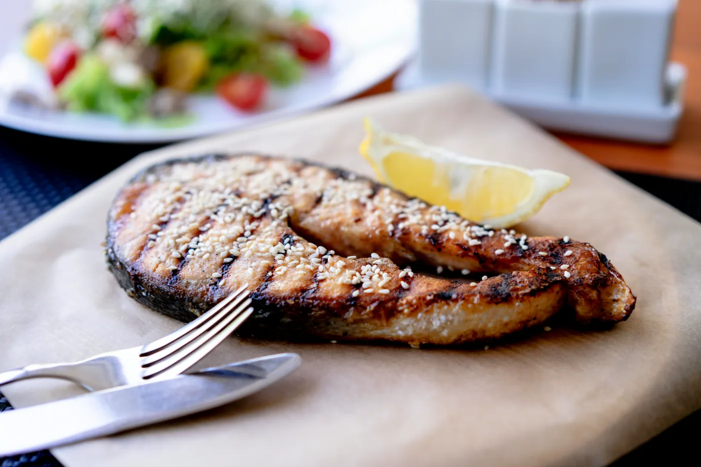Grilled salmon with lemon slice served on paper, perfectly illustrating popular preparation methods and the delicate flavor of salmon.
