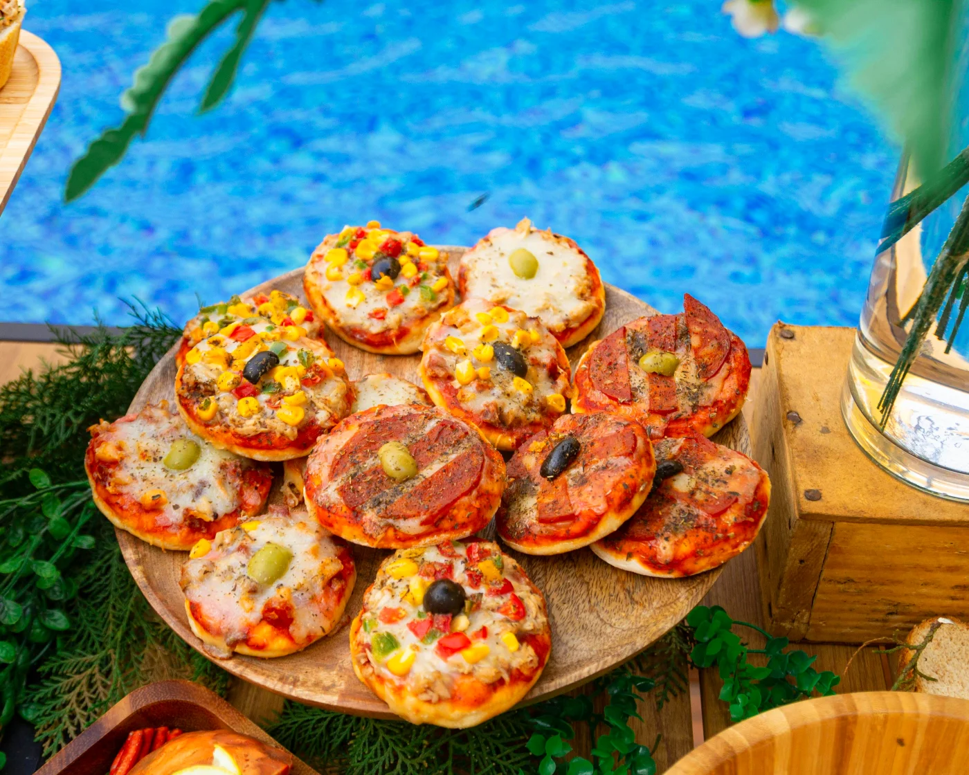 A tray with various mini-pizzas presented at a party, perfect for late-night food with varied toppings like olives and colorful vegetables.