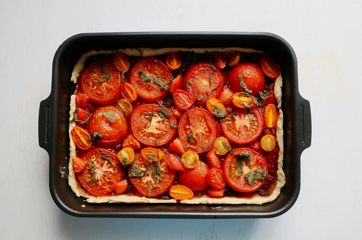 Tasty vegetable tart in a baking dish with fresh tomatoes and herbs - perfect for vegetarian late-night food.