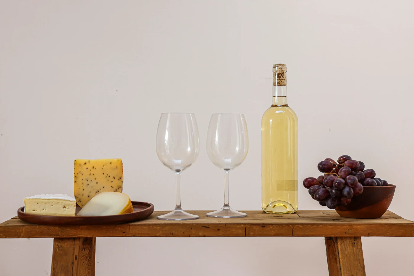 Elegant cheese platters with assorted cheeses, grapes, and white wine setup ready for festive appetizers.