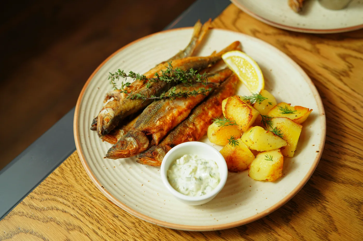 Lækre citron-dild kartofler serveret med stegt fisk, en citronbåd og dip, der fremhæver smagen af skaldyr.