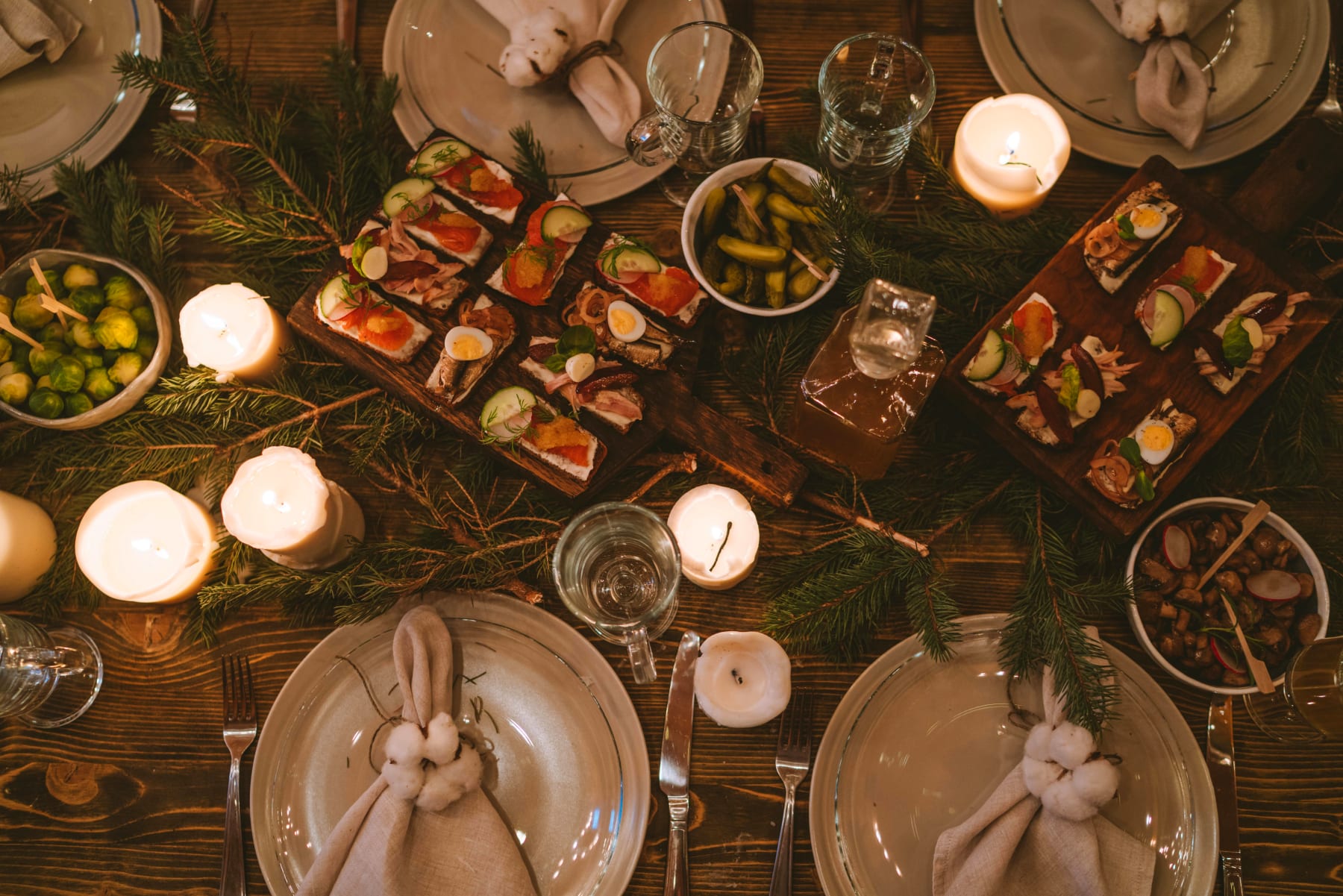 Easter breakfast table with rustic table setting, including decorative napkin bunnies and traditional dishes. Light and greenery create a cozy atmosphere, perfect for the Easter celebration.