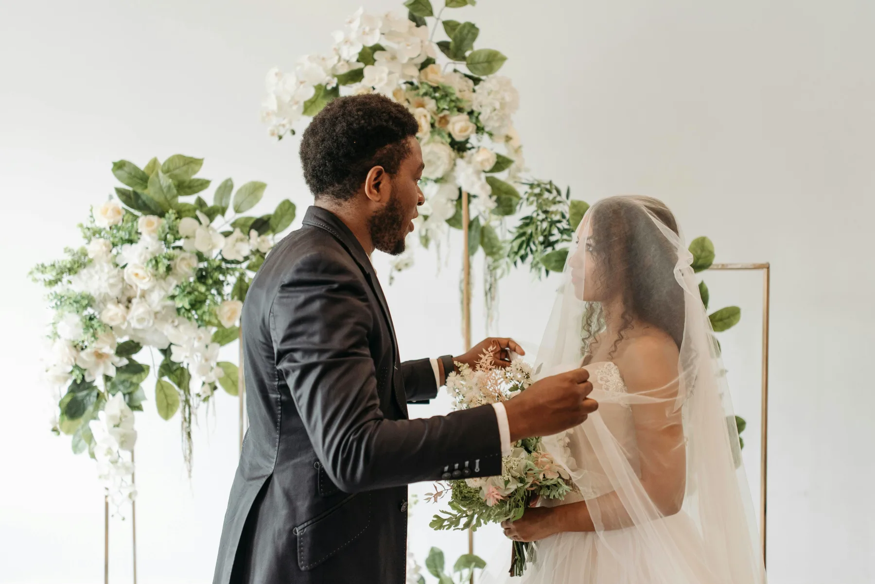Brudepar står foran blomsterdekorationer, symboliserer bryllupsdagens skønhed og planlægning.