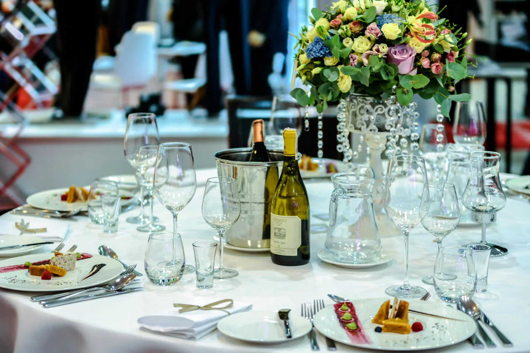 Elegant borddækning med blomsterarrangement til firmafest, klar til gourmetmiddag