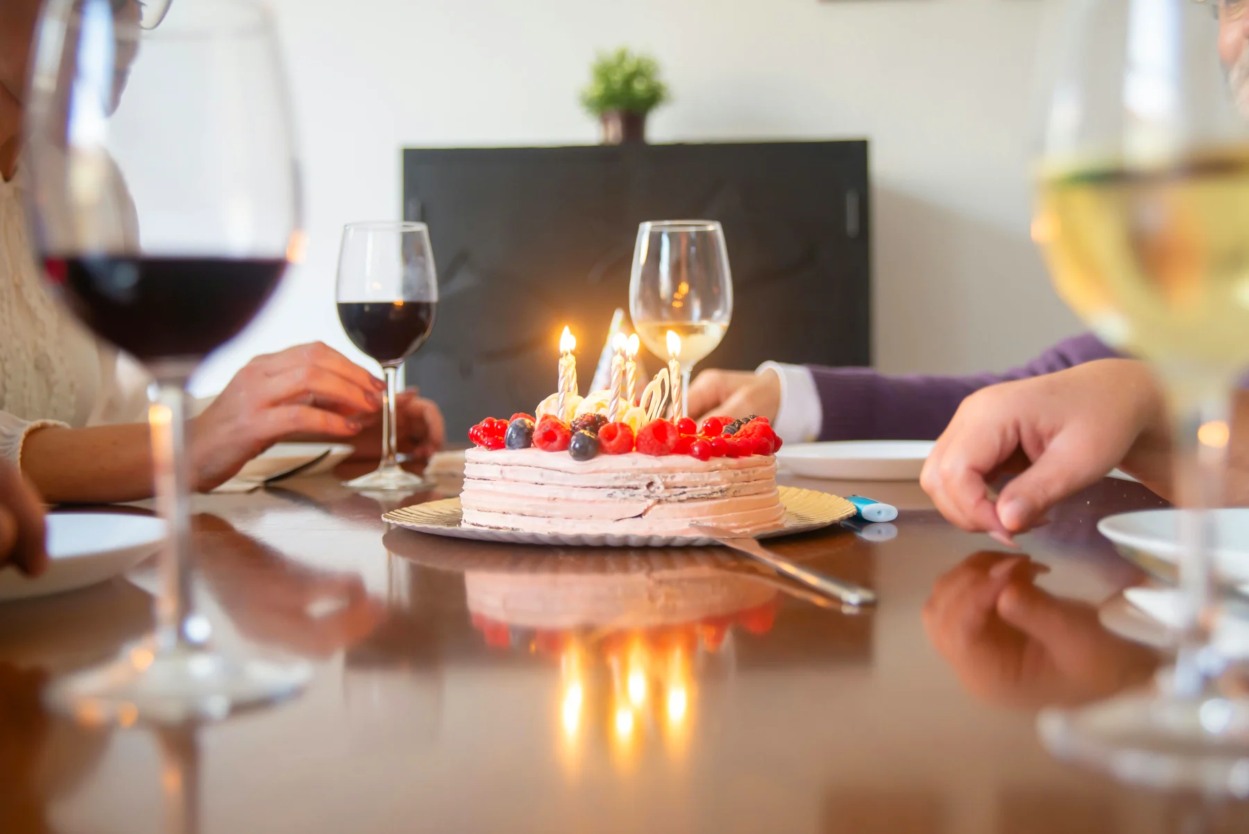 Birthday cake with live candles on a festive table with guests gathered for a 60-year birthday, highlighting the elegant celebration with a private chef.