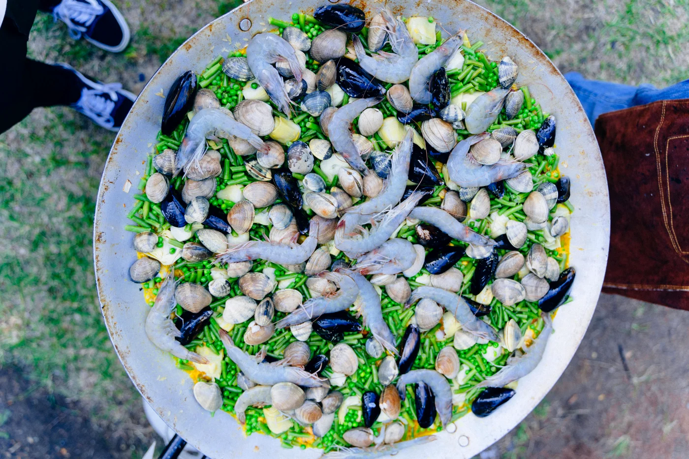 Stort fad med spansk paella, dekoreret med skaldyr og grøntsager, perfekt til en festlig fødselsdagsmenu.