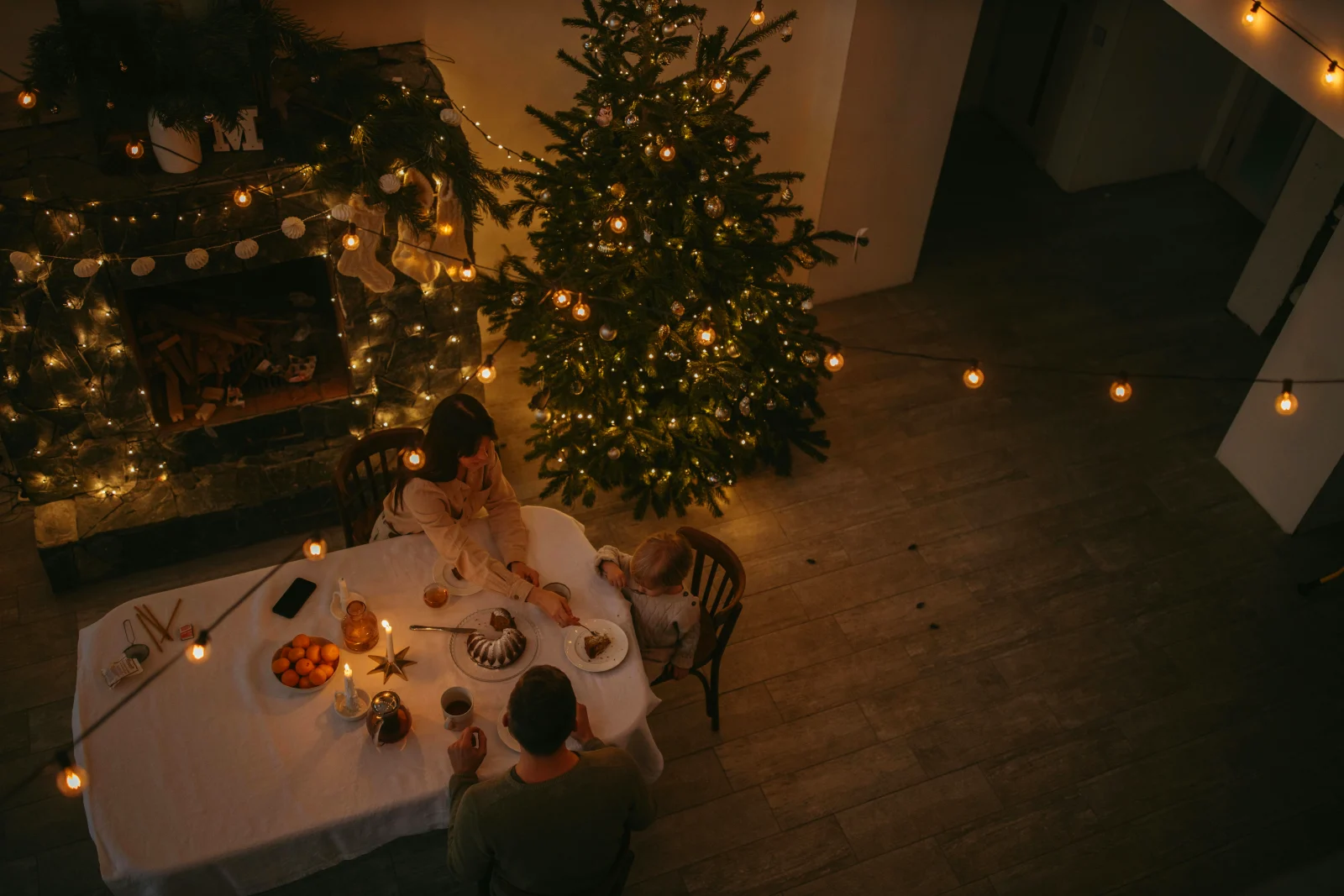 Julemiddag ved et festligt pyntet bord med juletræ og lys, skaber en hyggelig højtidstemning.