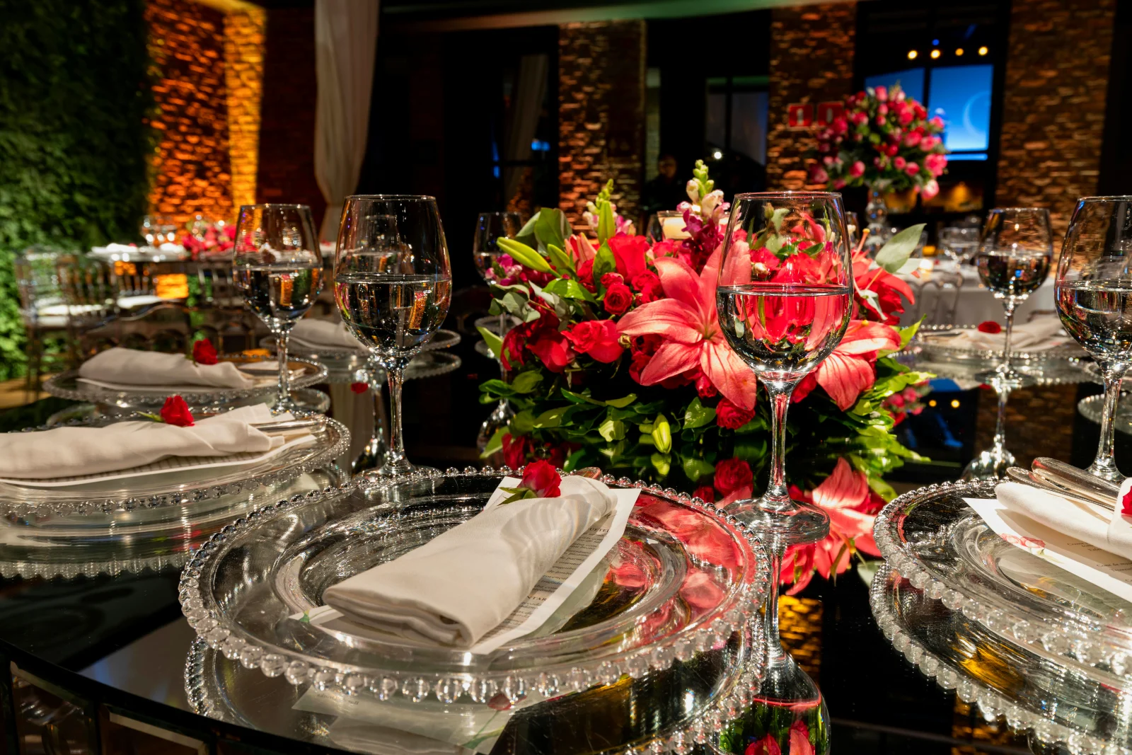 Smukt dekoreret bryllupsbord med elegante glas, servietter, og blomsterarrangement, som skaber en luksuriøs atmosfære.