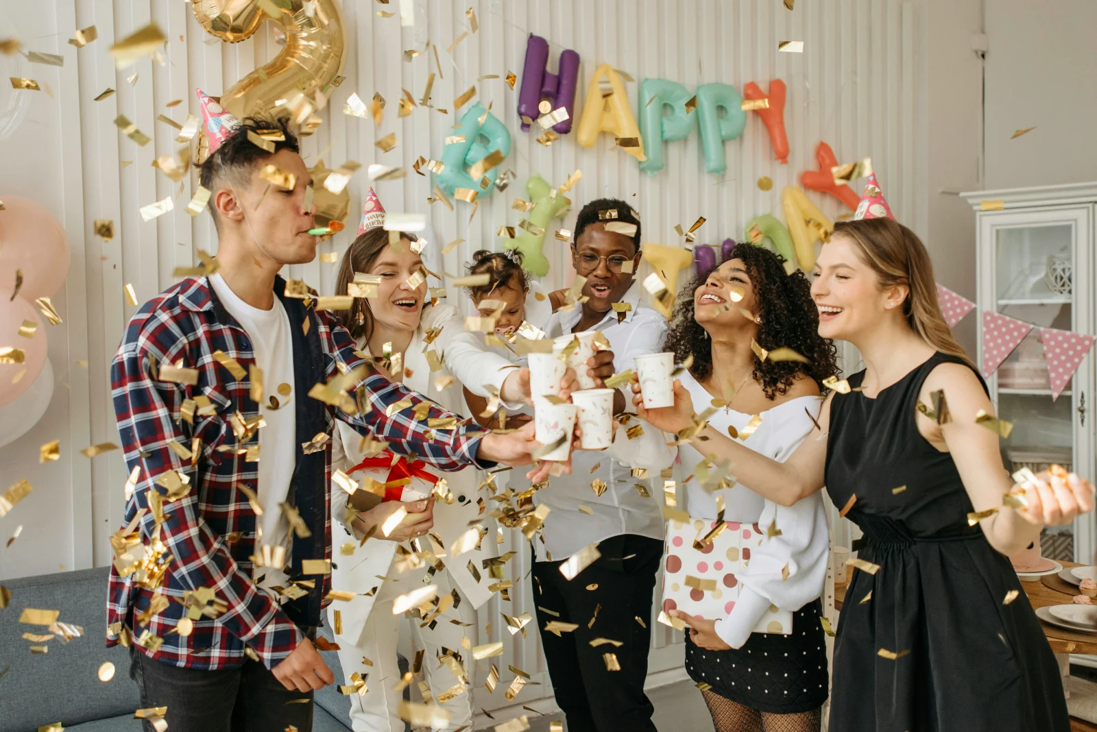 Glade mennesker fejrer med konfetti og drinks ved en fødselsdagsfest, perfekt til tips om at planlægge den ultimative fest.