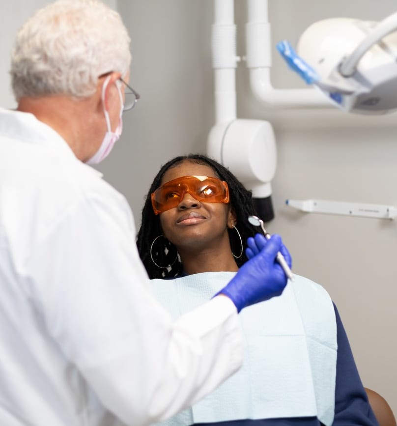 A dentist examining a patient wearing protective eyewear
