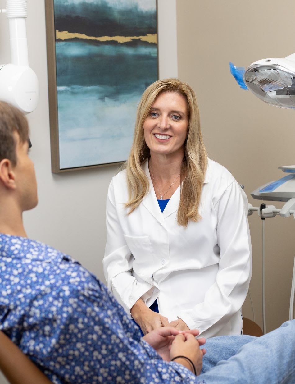A dentist talking with a patient in the exam chair