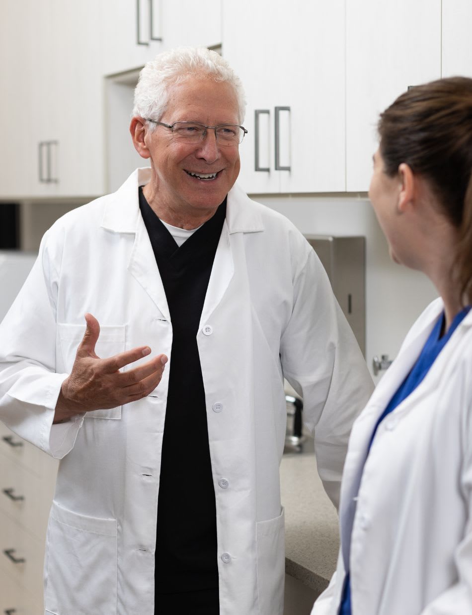 A dentist talking with a colleague in an exam room