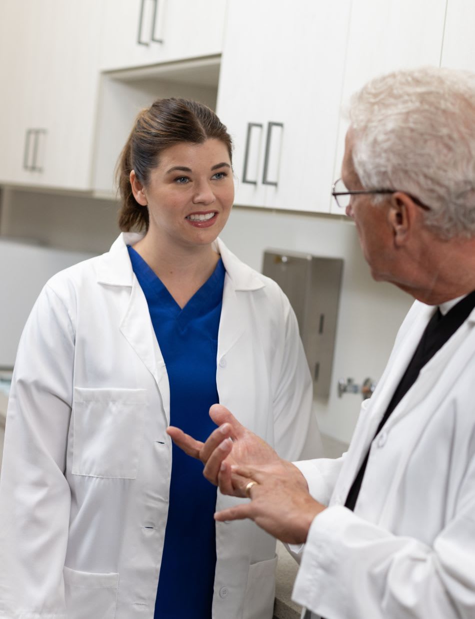 A dental team member in blue scrubs talking with a dentist