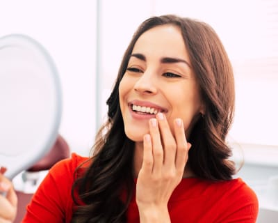 Smiling patient checking her new smile in a mirror