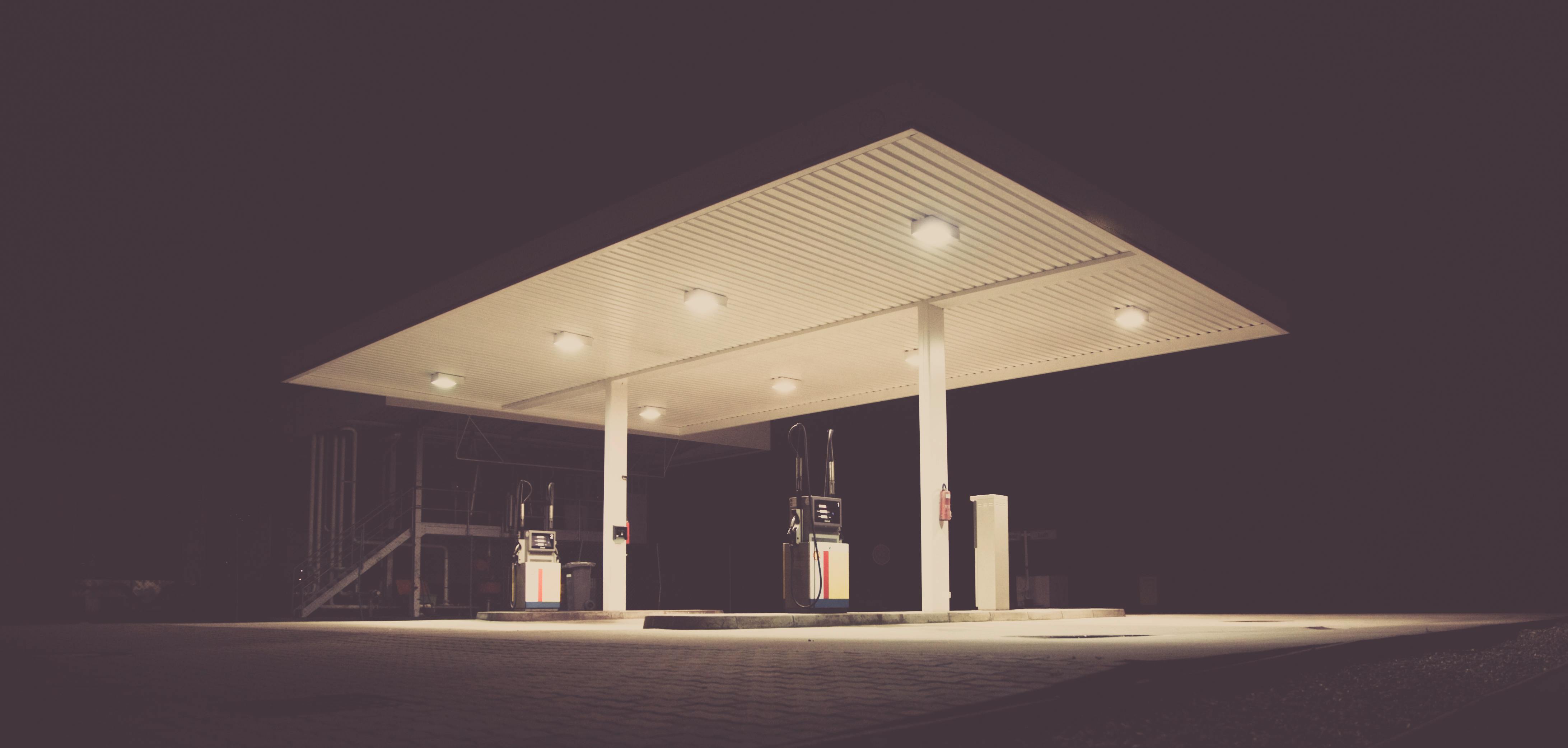 A dimly lit gas station at night, offering an eerie and calm atmosphere with dark surroundings.