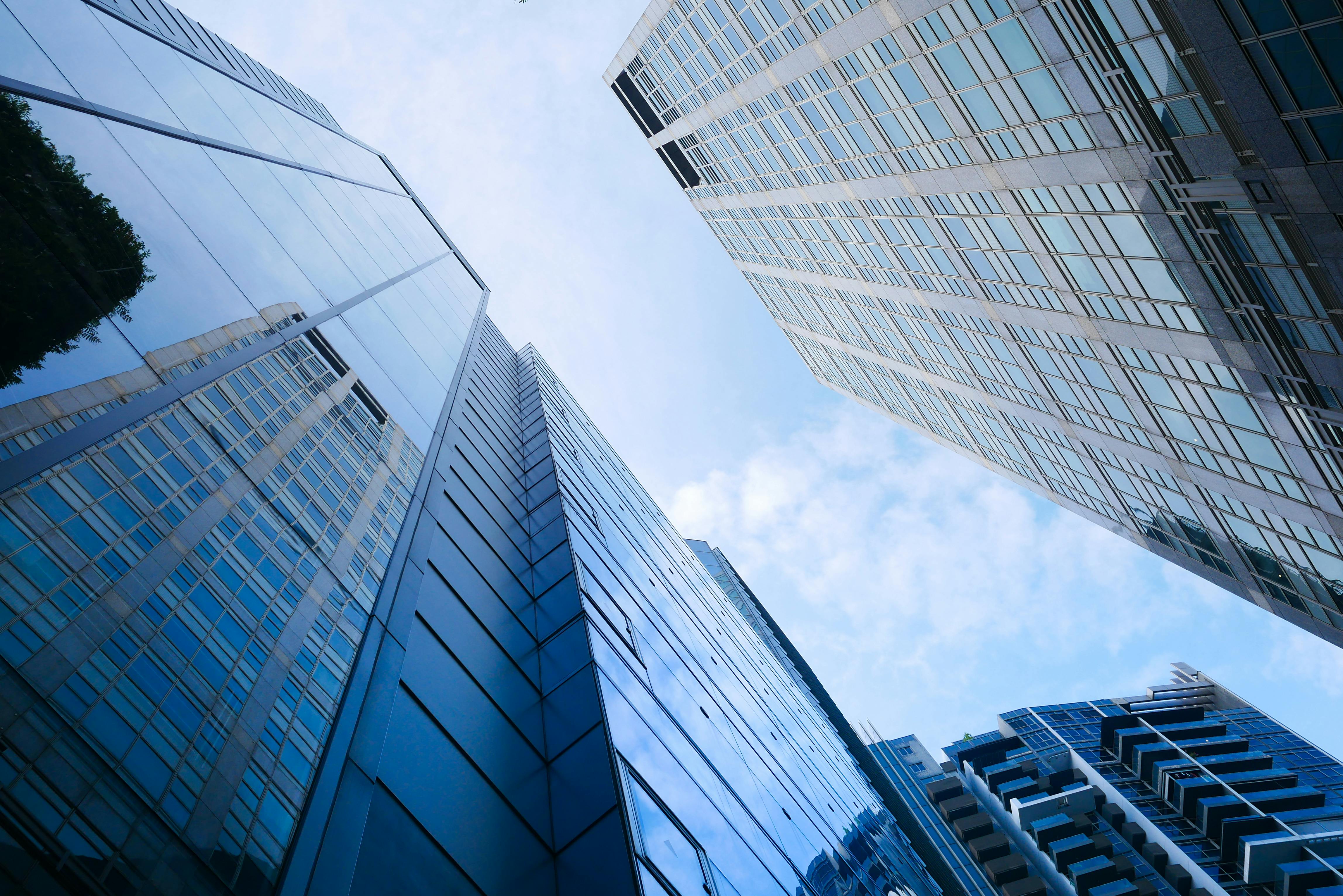 Low angle view of modern skyscrapers reflecting the sky, showcasing urban architecture.