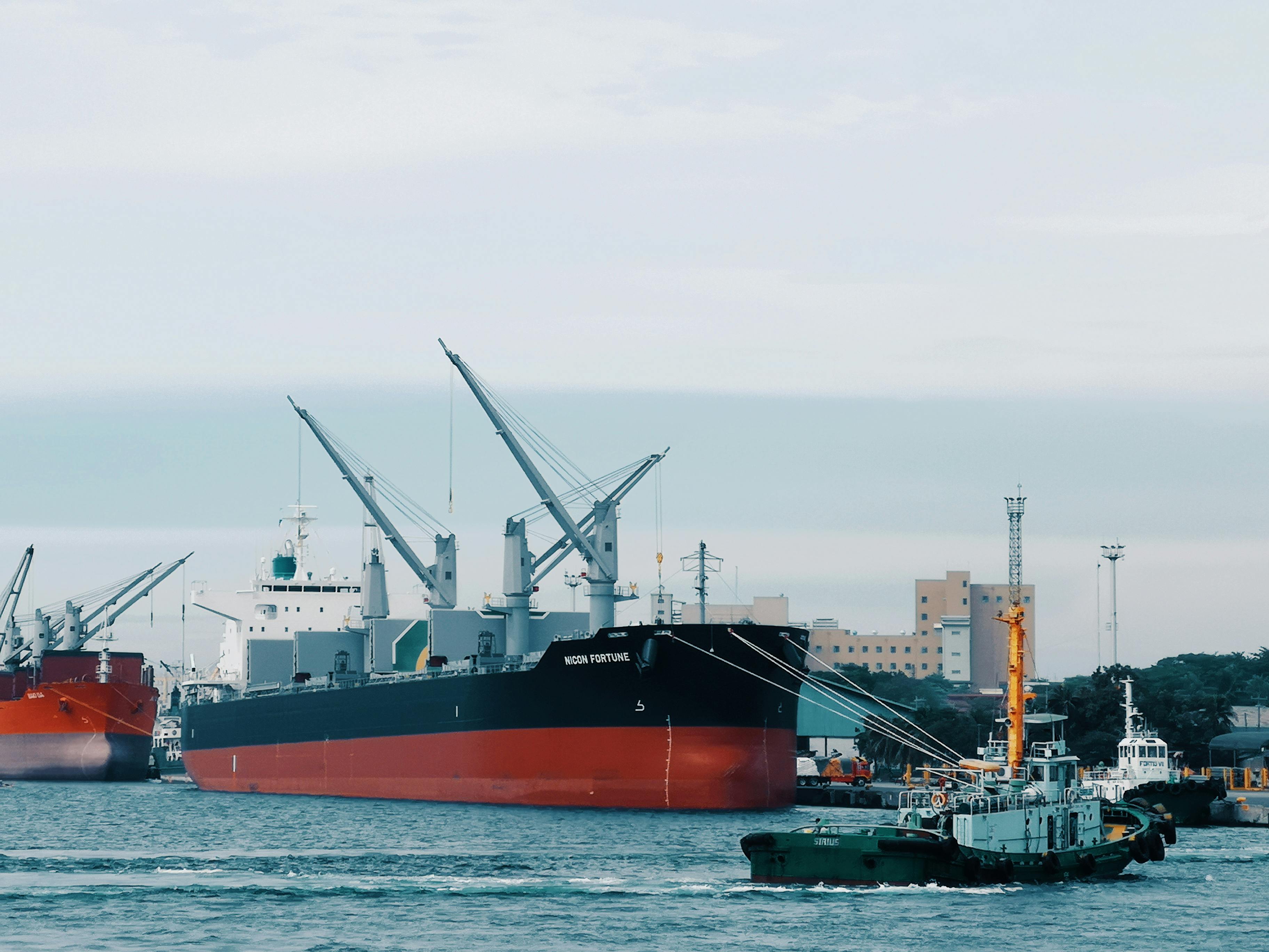 View of cargo ships docked at Davao harbor with tugboat assistance in Philippines.