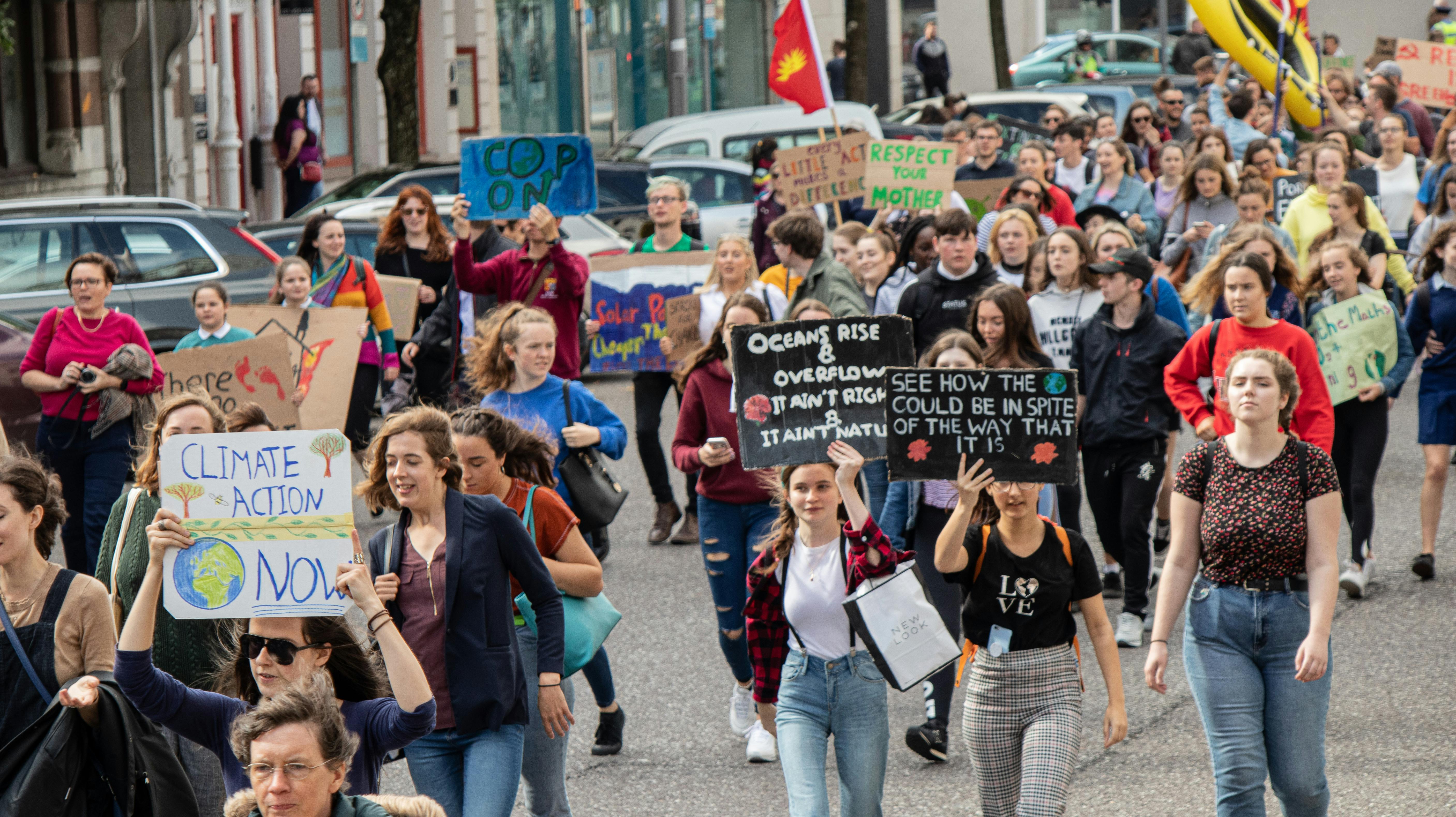 A vibrant climate march with diverse group holding signs demanding climate action.