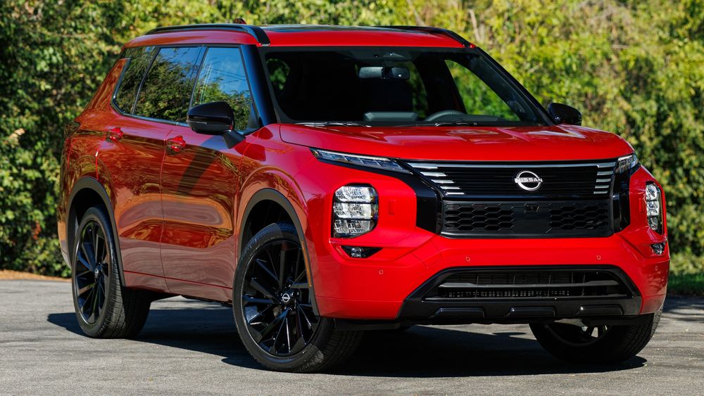 A Nissan Rogue displayed outside an illuminated dealership at night.