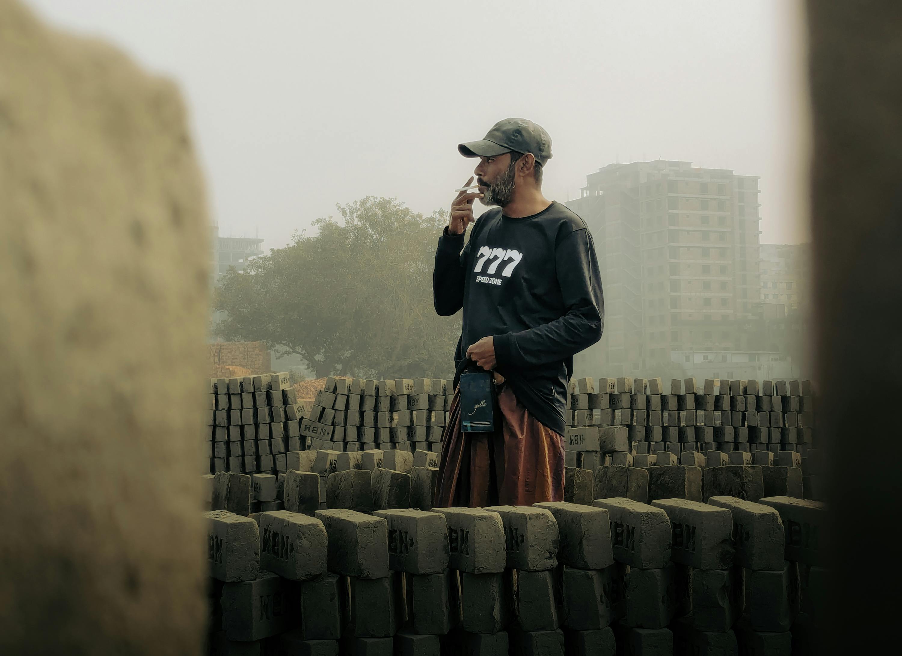Man wearing mask and gloves outside at dusk in a foggy landscape, symbolizing protection.