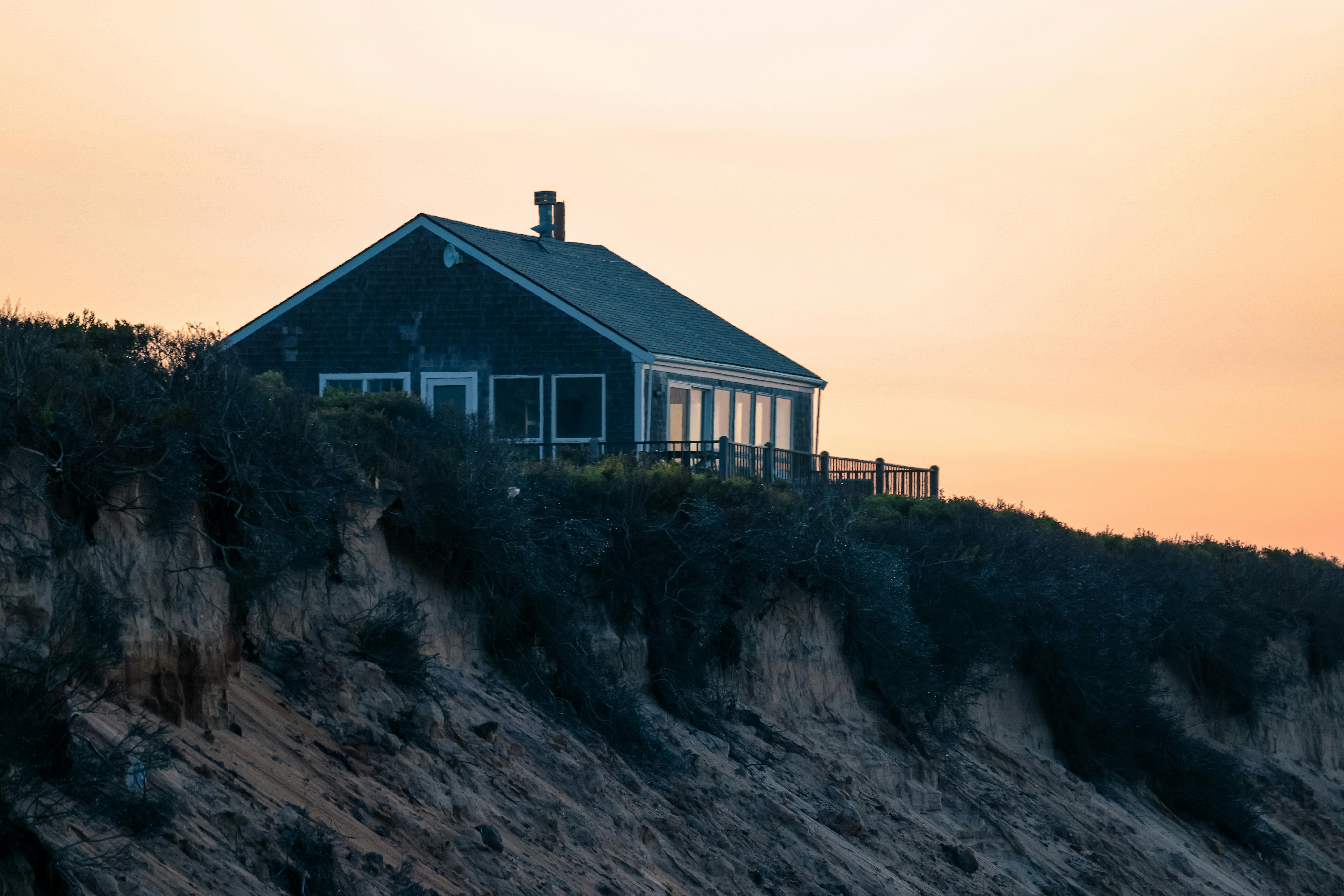 Quiet bungalow perched on Nantucket's cliffs with a serene sunset backdrop.