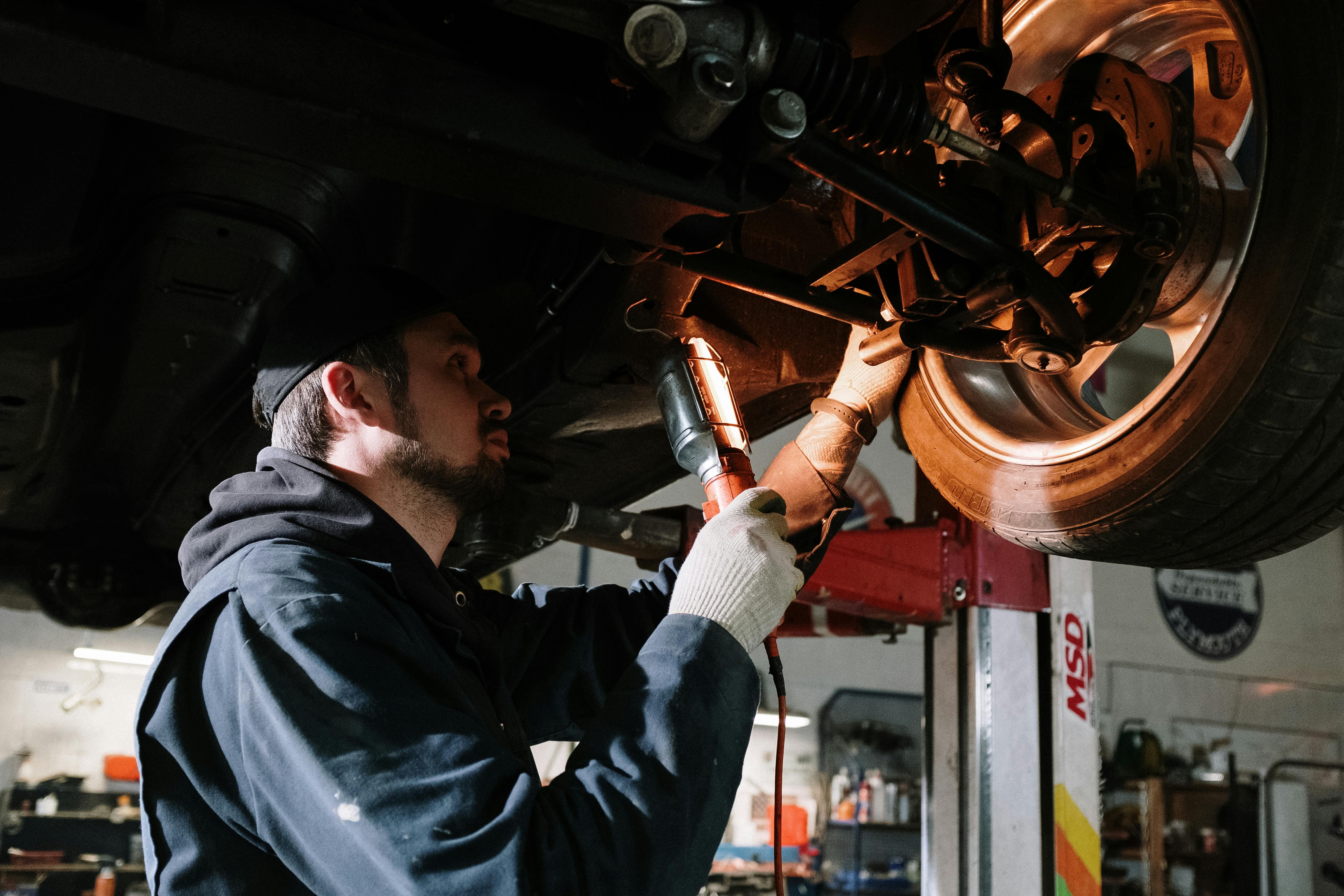 A mechanic working on a car engine with tools, focused on repairs.