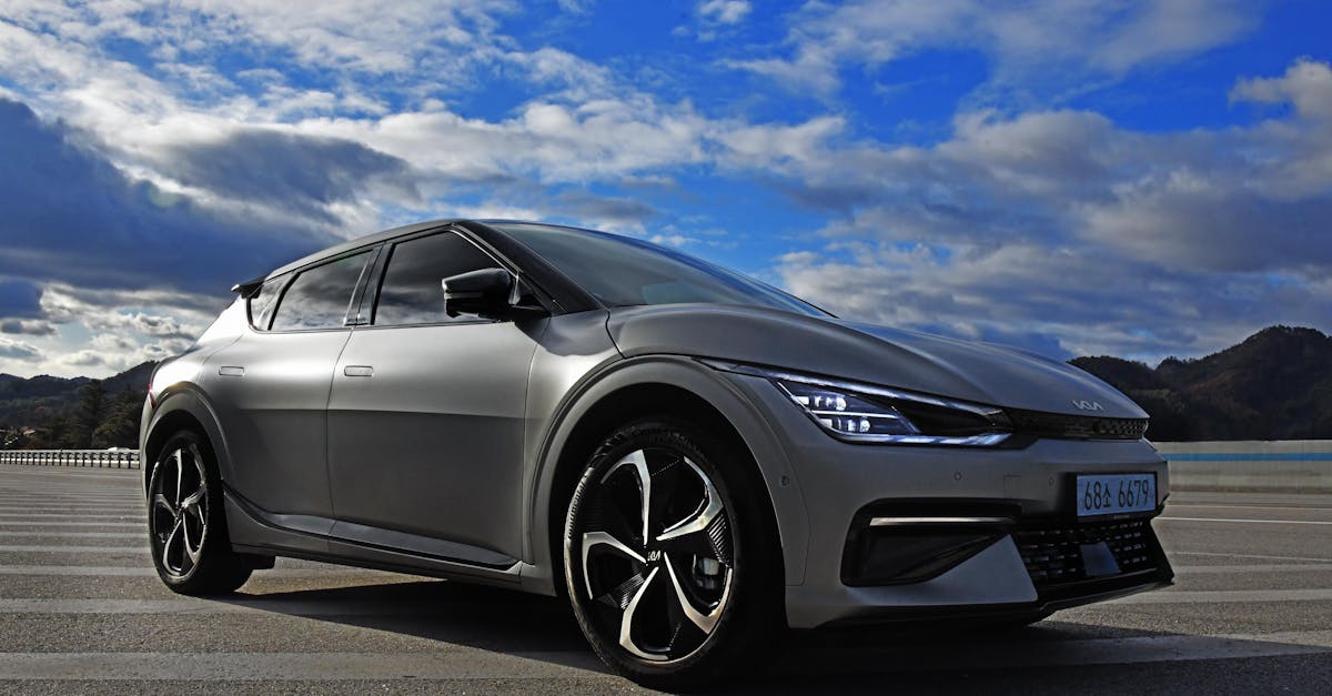 A sleek electric Kia EV6 parked outdoors against a stunning sky and landscape.