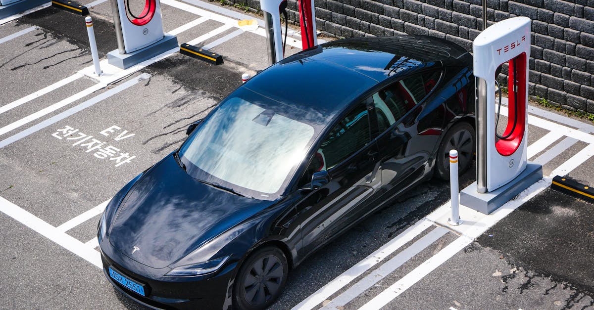 A black Tesla parked at a charging station in an urban setting.