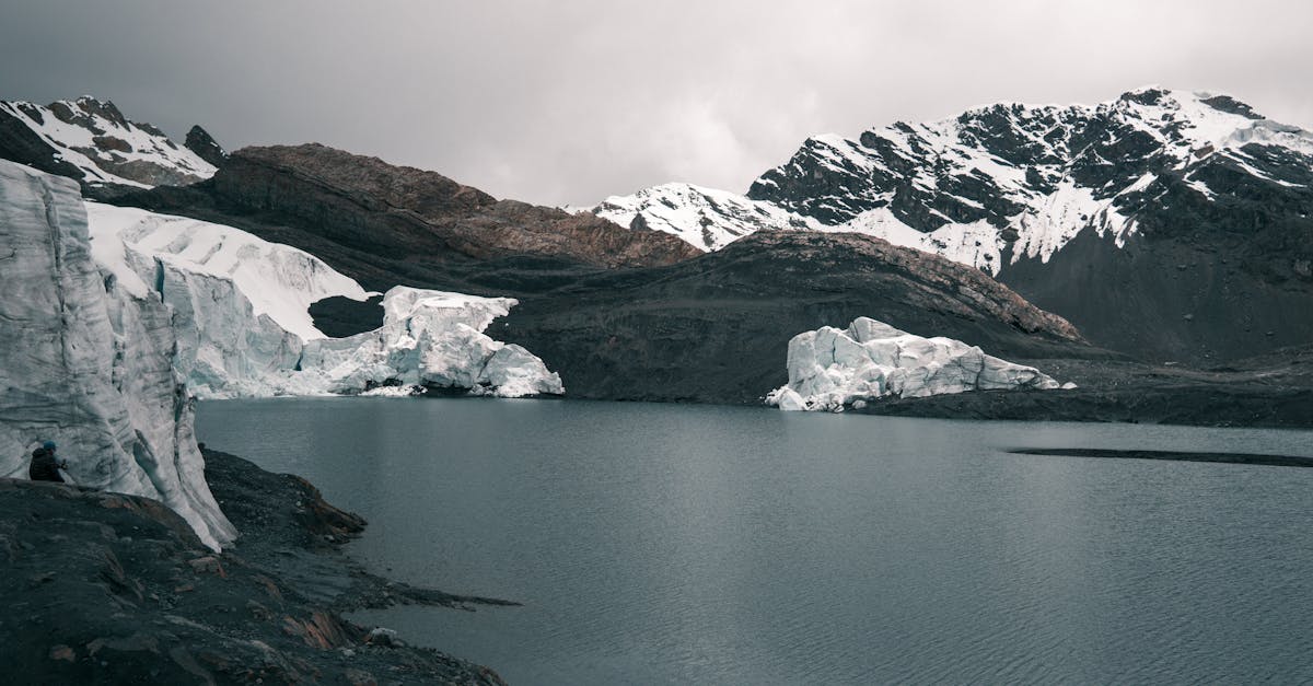 Serene view of a crystal-clear glacier lake in the Andes, surrounded by snowy peaks.