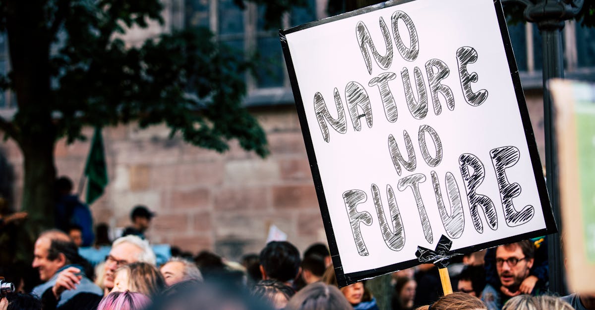 Large group of people rallying with a sign advocating for nature protection and climate action.