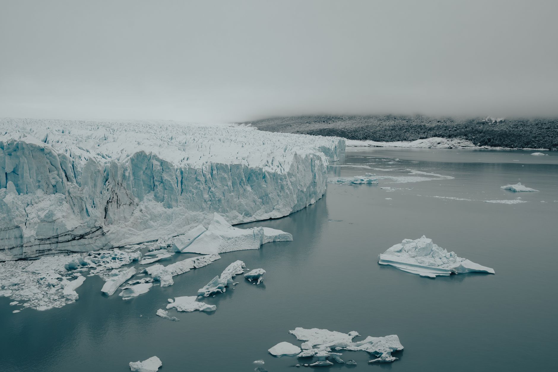 A vast icy landscape with glaciers and icebergs under a cloudy sky, showcasing natural beauty.