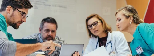 Multidisciplinary hospital team reviewing imaging workflow on a tablet during PACS procurement.&nbsp;