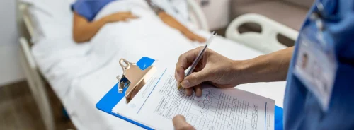 Healthcare professional recording patient information at the bedside, illustrating hospital care management, patient monitoring, and clinical documentation processes.&nbsp;