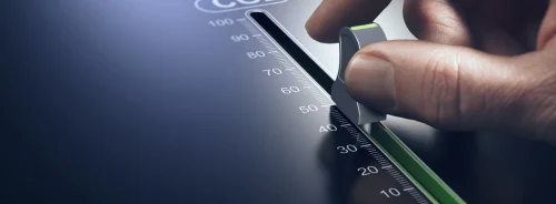 Hand adjusting a control knob to reduce CO₂ emissions,&nbsp;representing&nbsp;environmental sustainability, carbon footprint reduction, and green innovation efforts.&nbsp;