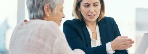 Professional consultation between an advisor and an older woman, reviewing information on a laptop.&nbsp;